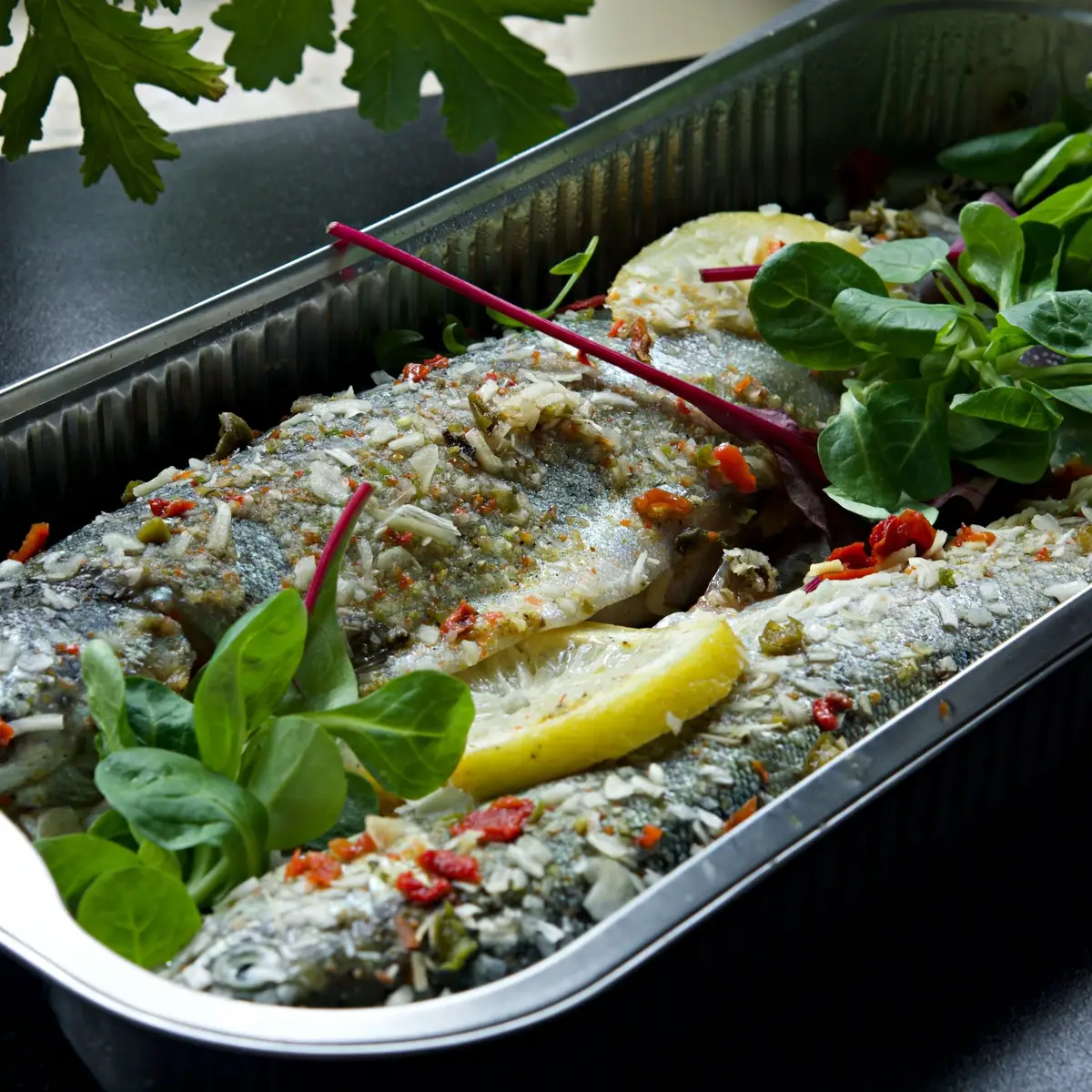 Poisson entier cuit au four, peau dorée, sur un plat